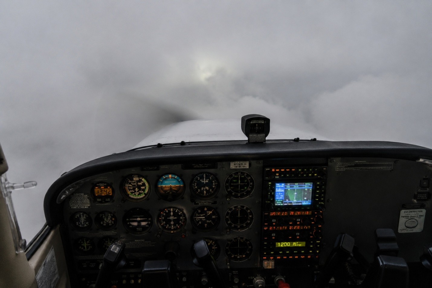 Cockpit instrument panel and forward view of an airplane flying in clouds.
